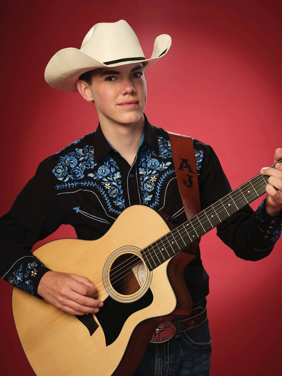 AJ Robinson in a white cowboy hat with his acoustic guitar