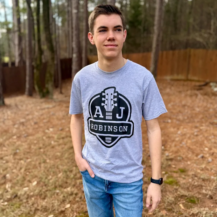AJ wearing a heather gray tee with the crest printed large across the chest