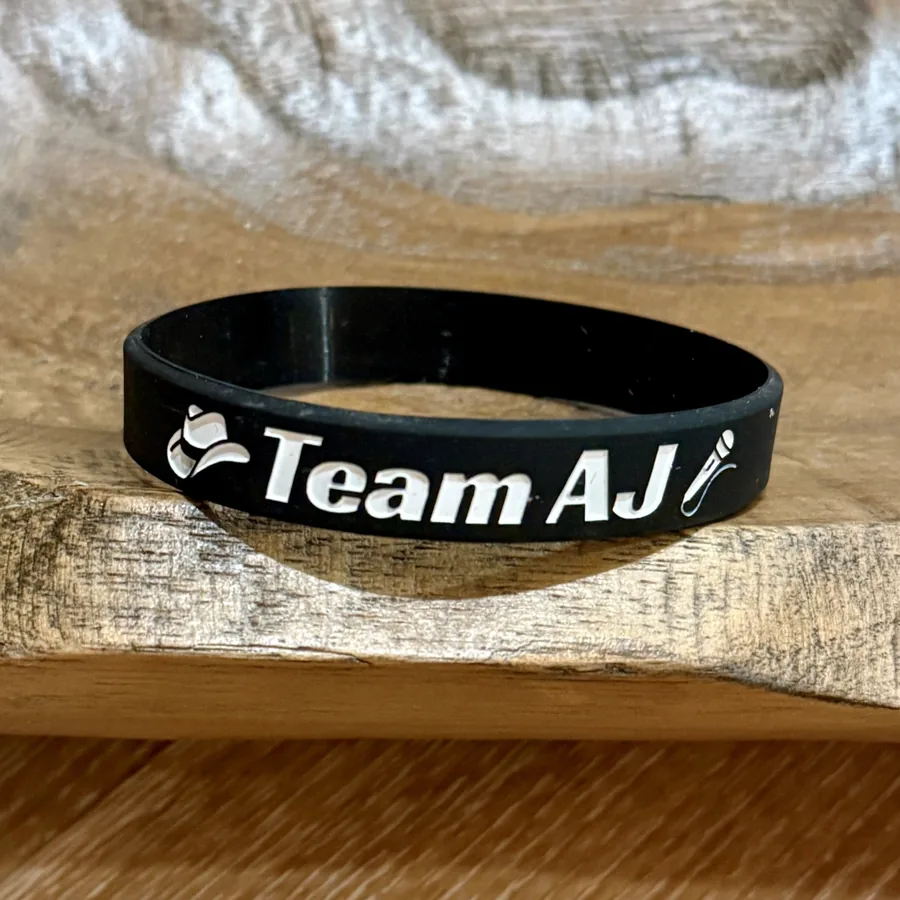 Black Team AJ silicone wristband with a cowboy hat and microphone icon